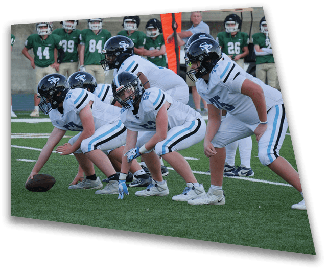 A group of football players in uniforms are on the field, with one player holding a football. AI generated content