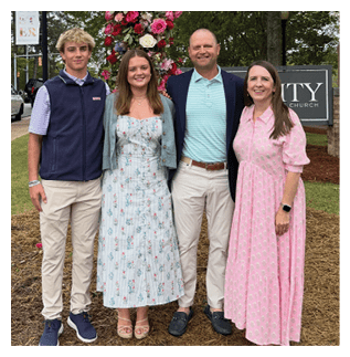 A group of four people pose for a photo in front of a large cross. AI generated content