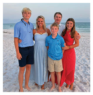 A group of five people, including a woman and a child, pose for a picture on a beach. AI generated content