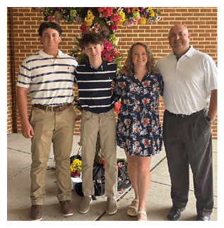 A family poses for a picture in front of a flower arrangement. AI generated content