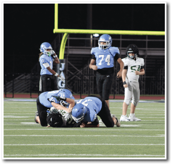 Two football players are on the ground, one on top of the other, during a game. AI generated content