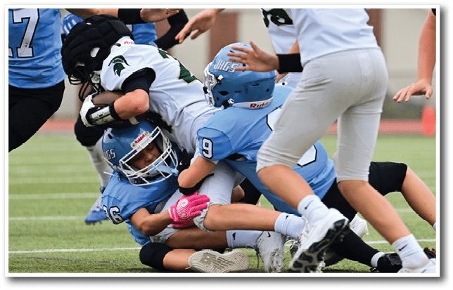 A group of young men playing football on a field. One player is tackled to the ground. AI generated content