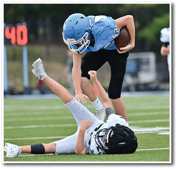 Two boys are playing football on a field. One boy is tackling the other boy to the ground. AI generated content