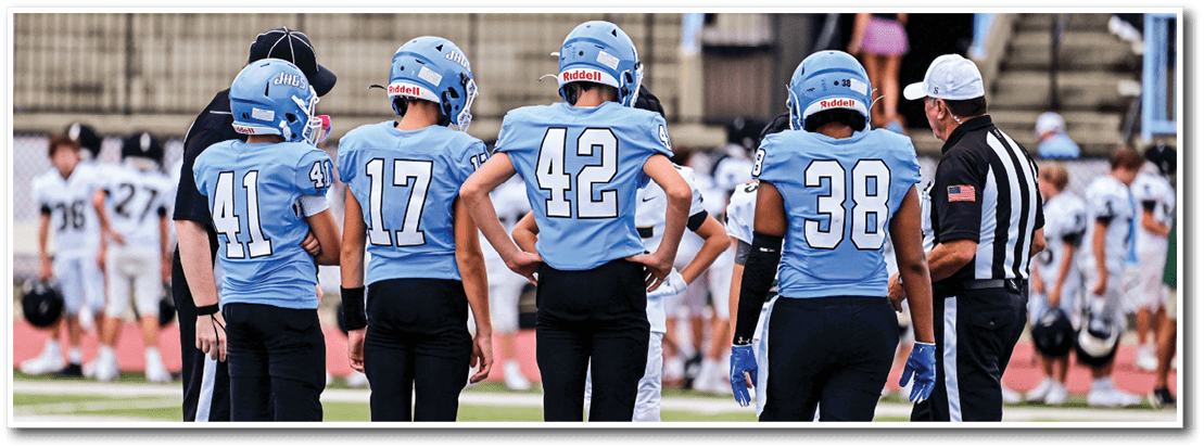 A group of young boys wearing blue jerseys stand on a field, waiting for the referee to make a call. AI generated content