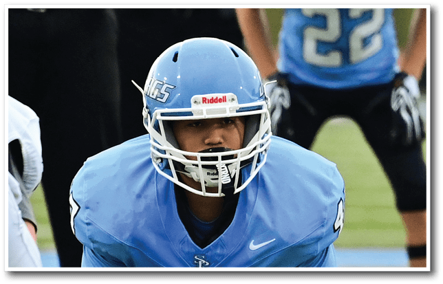 A football player wearing a blue helmet and jersey is kneeling on the field. AI generated content