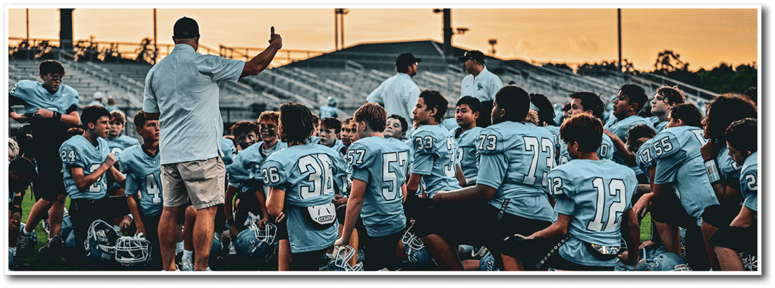A group of young men are kneeling on a field, listening to a coach. AI generated content