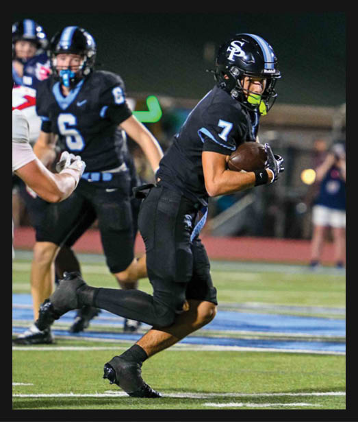 A person wearing a black football uniform with the number 7 is running with the ball on a football field while another person in a similar uniform with the number 6 is in the background. Description generated by AI