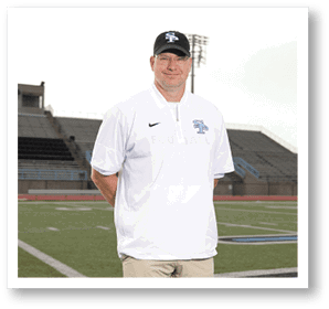 A man wearing a white shirt and a black hat stands on a football field. AI generated content