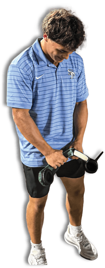 A person wearing a blue striped polo shirt and black shorts is holding and examining a black and green handheld device. Description generated by AI