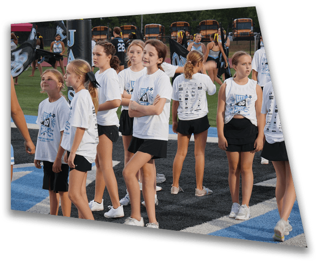 A group of people wearing athletic clothing and sneakers are standing on a sports field with blue and black markings. Description generated by AI