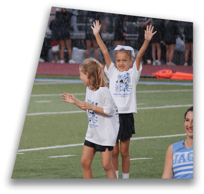 People in athletic clothing are raising their arms and smiling on a sports field during a rainy event. Description generated by AI