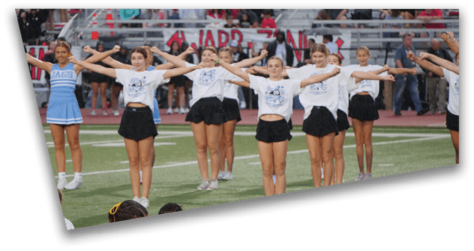 A group of people in cheerleading uniforms and athletic clothing are performing a coordinated routine on a sports field. Description generated by AI