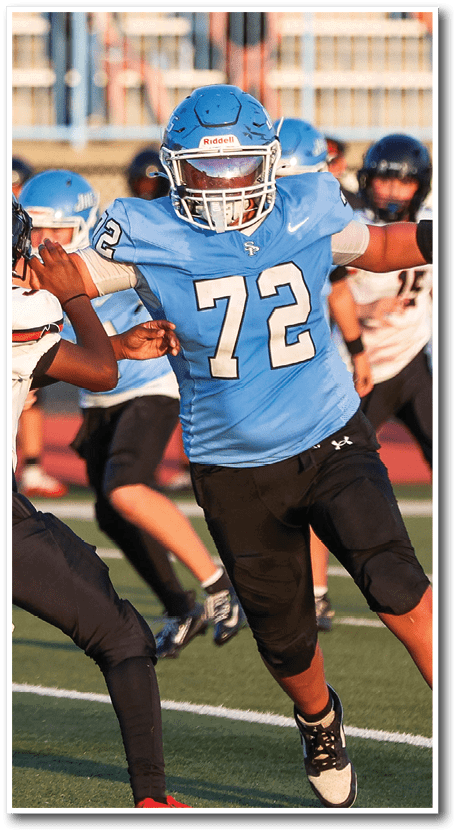 A person wearing a blue football jersey with the number 72 is actively engaged in a game on a football field with other players in the background. Description generated by AI