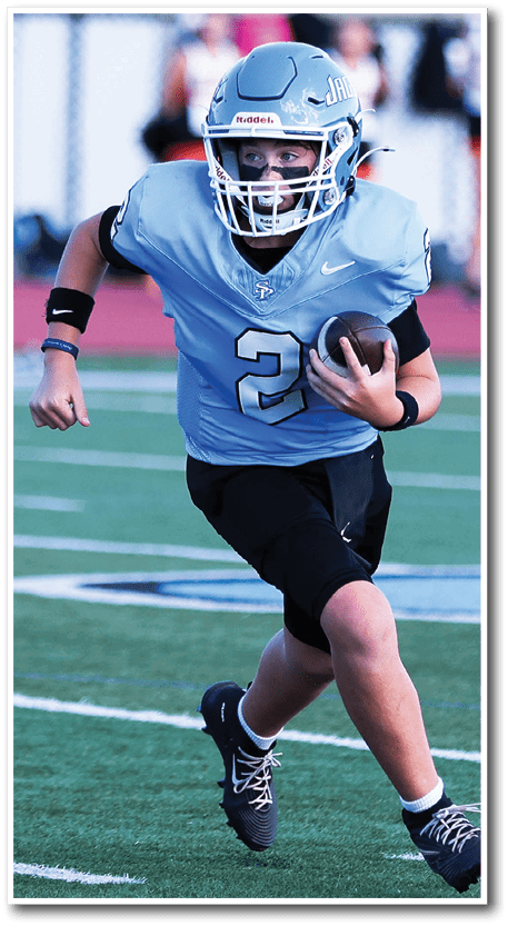 A person wearing a blue football jersey with the number 72 is actively engaged in a game on a football field with other players in the background. Description generated by AI