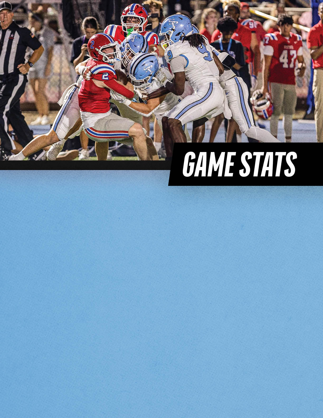 Several people in football uniforms are engaged in a tackle during a game with a crowd and referee visible in the background. Description generated by AI