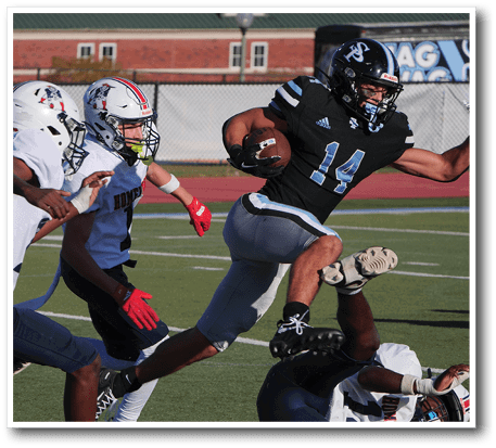 A person in a black football uniform with the number 14 is running with the ball while three people in white football uniforms attempt to tackle them on a green field. Description generated by AI