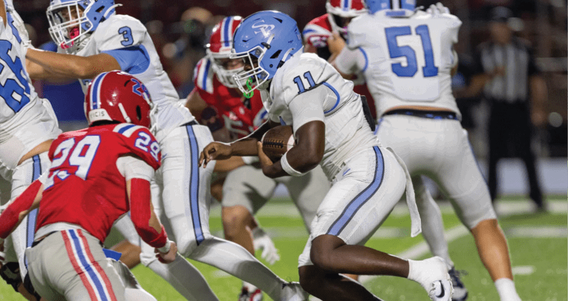 Several people in football uniforms are actively engaged in a play on a grassy field during a game. Description generated by AI