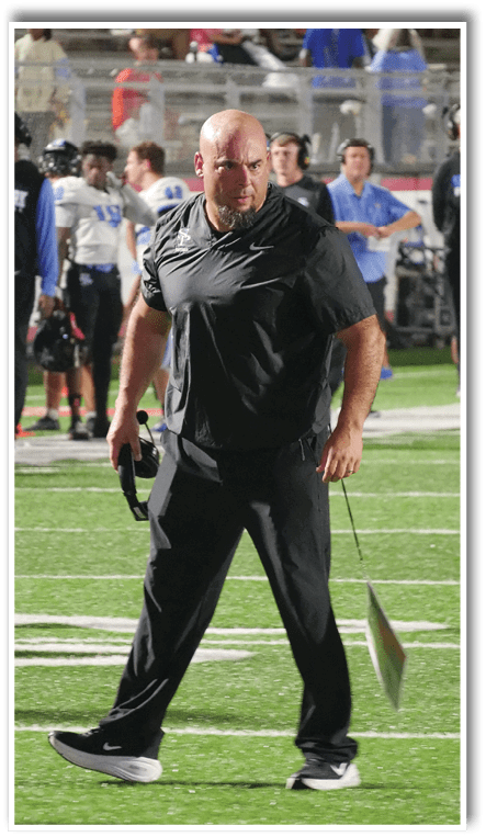 A person wearing a black shirt and black pants standing outdoors. Description generated by AI