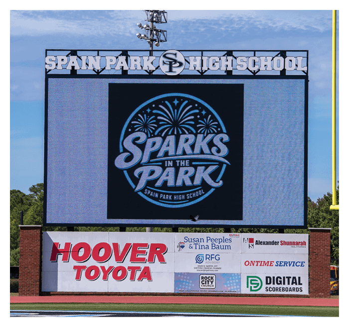 A large digital scoreboard at Spain Park High School displays the logo for Sparks in the Park with advertisements for Hoover Toyota and other local businesses below. Description generated by AI
