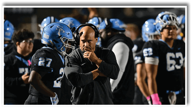 A group of people wearing football helmets and uniforms are gathered on a field with one person in a headset appearing to give instructions. Description generated by AI