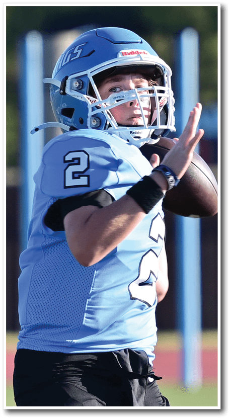 A person wearing a light blue football helmet and uniform is looking intently to the side. Description generated by AI