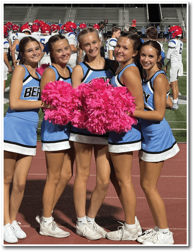 People wearing blue and white cheerleading uniforms hold bright pink pom-poms while standing on a track. Description generated by AI