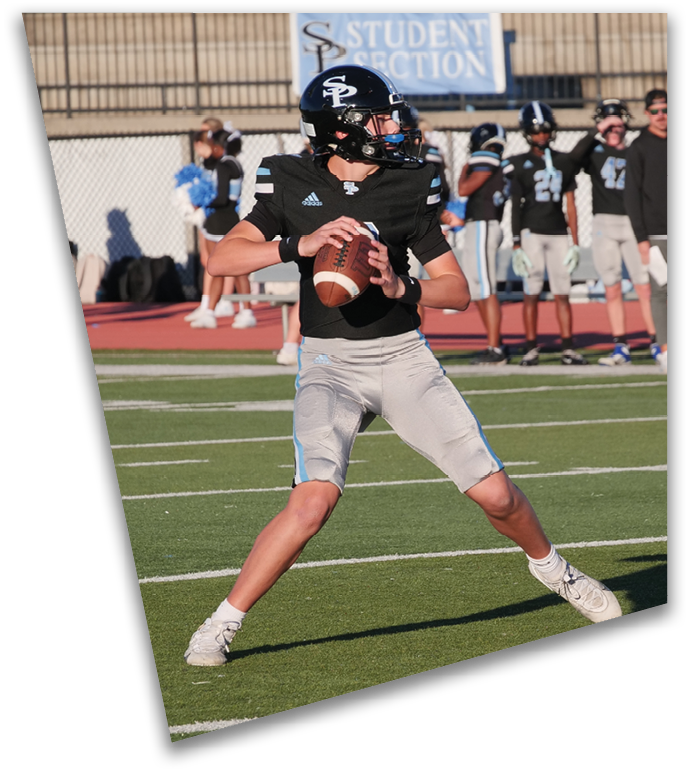A person in a black football uniform and helmet is holding a football and preparing to throw it on a green field with other players and a sign reading “Student Section" in the background. Description generated by AI