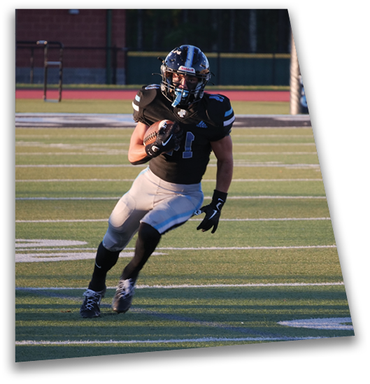 A person wearing a black football uniform and helmet is running on a football field while holding a football. Description generated by AI