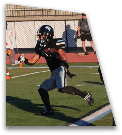 A person wearing a football helmet and uniform is running on a football field while other players with gloves and cleats are nearby. Description generated by AI