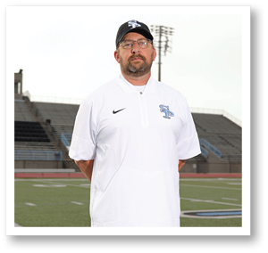 A man wearing a white shirt and a cap stands on a football field. AI generated content