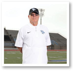 A man wearing a white shirt and a black hat stands on a football field. AI generated content