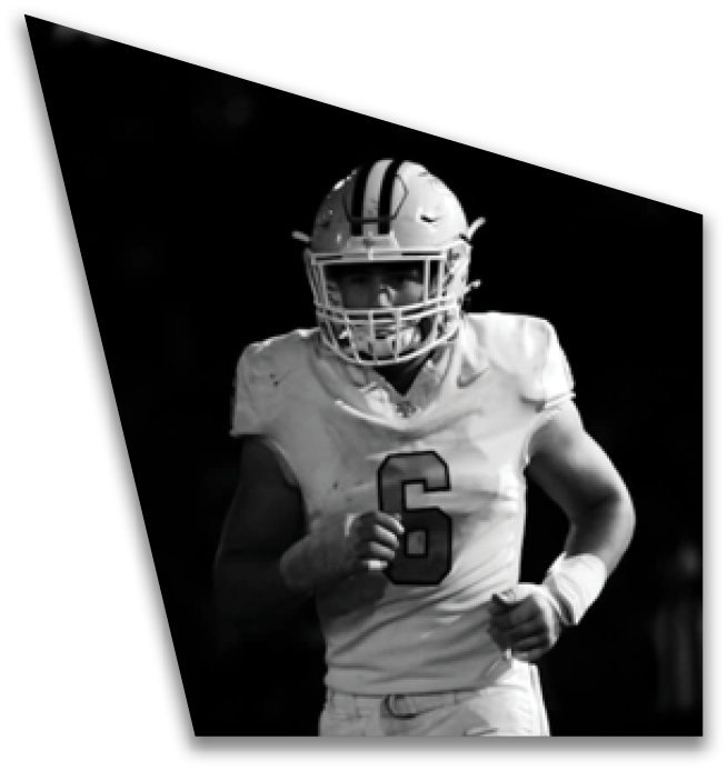 An adult wearing a football uniform with the number two is running on a field at night. Description generated by AI