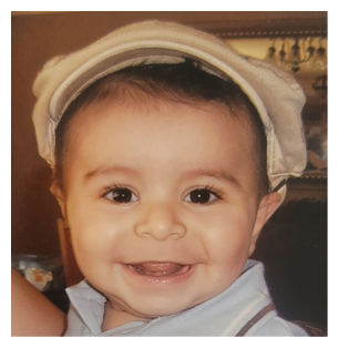 A young boy wearing a blue shirt and a hat is smiling for the camera. AI generated content