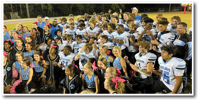 A group of cheerleaders and football players pose for a photo on the field. AI generated content