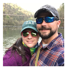A man and woman are standing next to each other, posing for a photo. The man is wearing a plaid shirt and sunglasses, while the woman is wearing a hat. They are both smiling and enjoying their time together. AI generated content