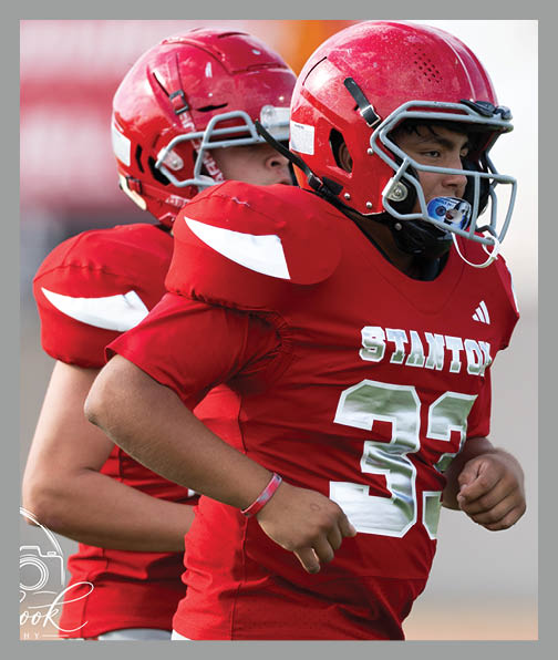 A football player in a white uniform is running with a football in his hand. AI generated content