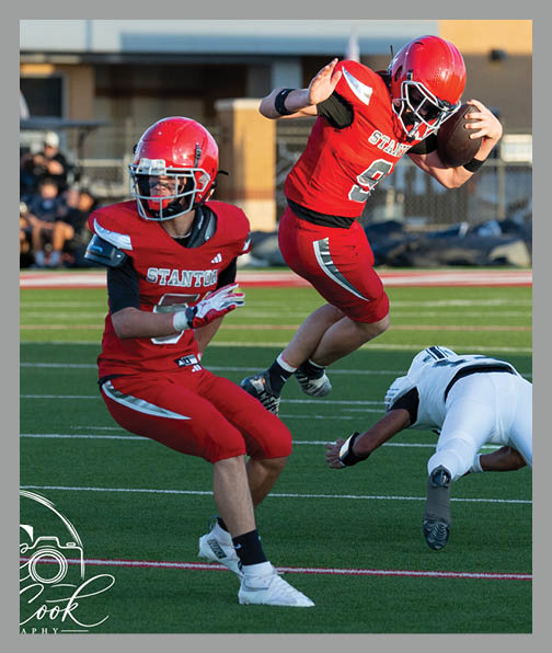 A football player in a white uniform is running with a football in his hand. AI generated content