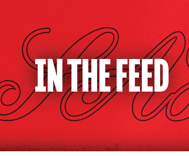 The text “IN THE FEED" is displayed in bold white capital letters over a red background with a faint black cursive design. Description generated by AI