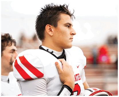 A person with spiked hair wearing a white sports jersey is looking to the side with a focused expression. Description generated by AI