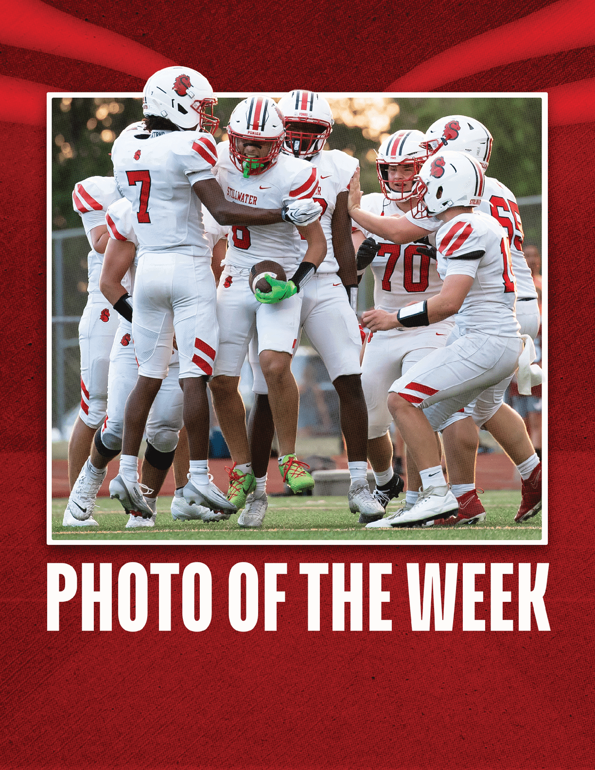 A group of people in white football uniforms with red accents are gathered on a field, celebrating or strategizing during a game. Description generated by AI
