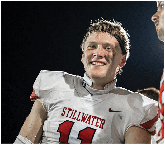 Two people wearing white football helmets with red faceguards and a red lion logo are focused and looking ahead. Description generated by AI