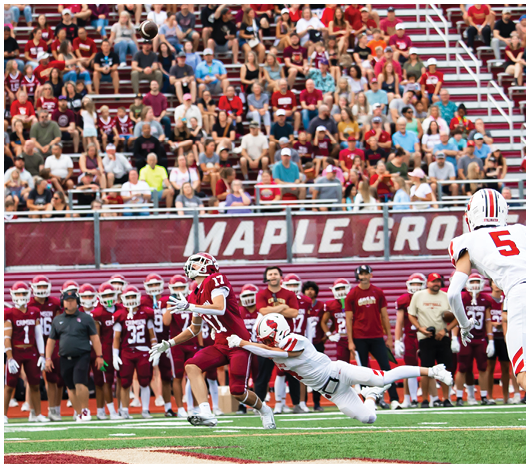 Two people wearing white football helmets with red faceguards and a red lion logo are focused and looking ahead. Description generated by AI