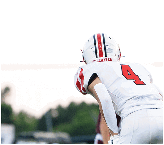 Several football players in helmets and uniforms are engaged in a tackle on a field with yard lines visible. Description generated by AI