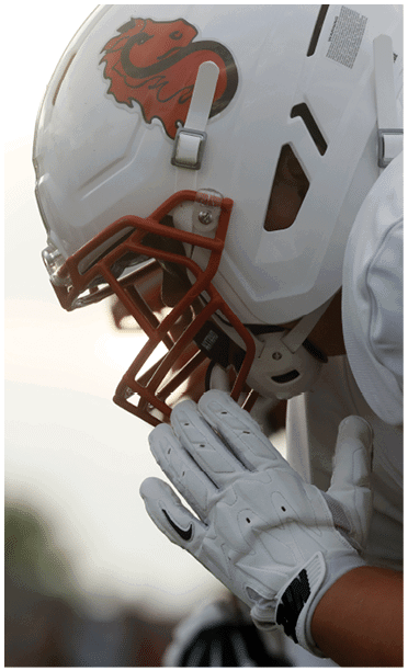 A person wearing a white sports uniform and helmet is holding their hands together near their face, wearing white gloves with a black Nike logo. Description generated by AI