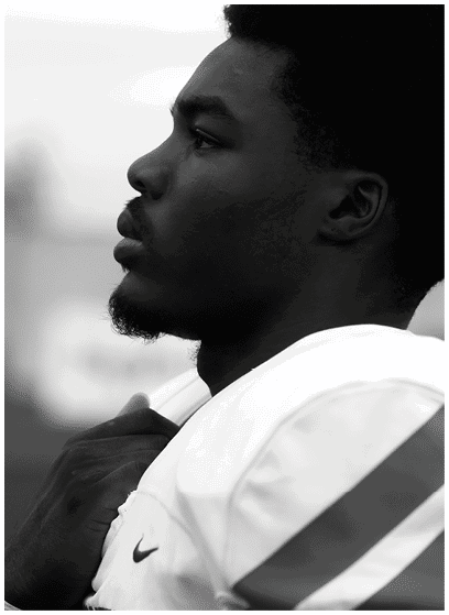 A person wearing a sports jersey is shown in profile with a focused expression, holding the collar of the jersey. Description generated by AI