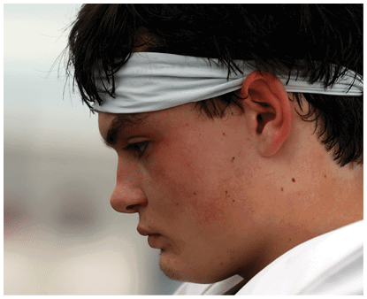A person with dark hair wearing a white headband is shown in close-up profile view against a blurred background. Description generated by AI