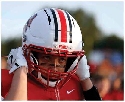 A person wearing a white football helmet with red and black stripes and a red jersey is adjusting the helmet while looking ahead with black face paint under their eyes. Description generated by AI