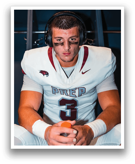 A person wearing a white football jersey with “PREP" on the front and black eye paint is sitting and wearing large black headphones. Description generated by AI