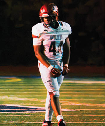 A person in a football uniform with the number 4 and the word “PREP" on the jersey is standing on a football field at night. Description generated by AI