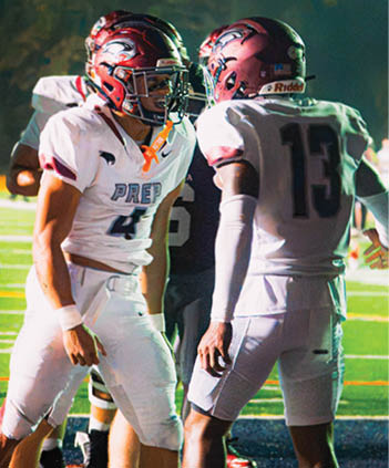 Two people in football uniforms and helmets are standing on a field, facing each other, with one wearing number 13 and the other number 41. Description generated by AI